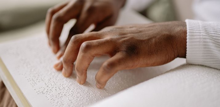 Deux mains lisent un livre en braille.